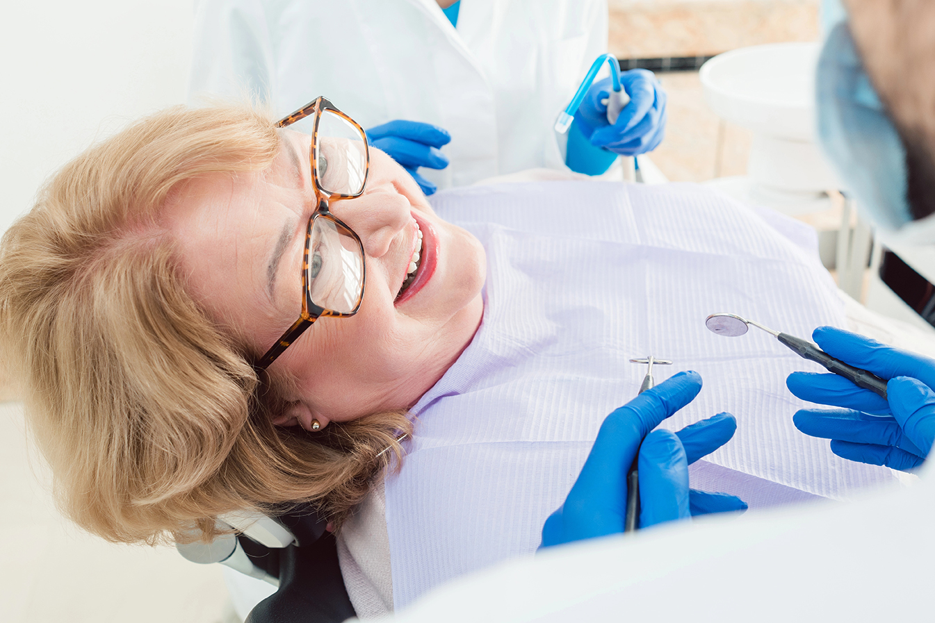 Team of dentists talking to senior patient in their surgery explaining the treatment
