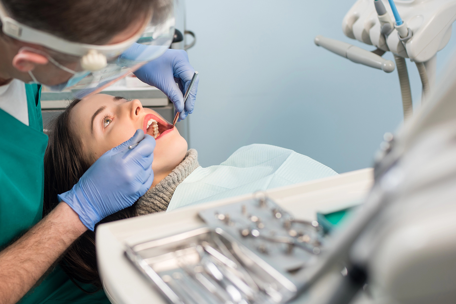 Male dentist with dental tools - mirror and probe checking up patient teeth at dental clinic office. Medicine, dentistry and health care concept. Dental equipment