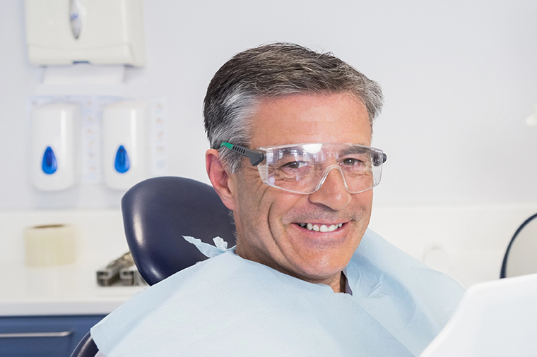 Smiling patient holding a mirror with a dentist behind him